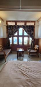 a bedroom with a bed and two chairs and a window at Hotel The Oak in Tawang