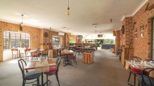 a restaurant with tables and chairs and a brick wall at Country 2 Coast Motor Inn Coffs Harbour in Coffs Harbour