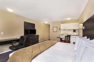a bedroom with a bed and a desk and a kitchen at Super 8 by Wyndham West Kelowna BC in West Kelowna