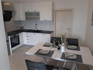 a kitchen with a table and chairs and a kitchen with white cabinets at LANELU apartman in Rogoznica