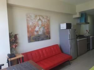 a red couch in a kitchen with a painting on the wall at KC Studio 2 at Horizon 101 Cebu in Cebu City