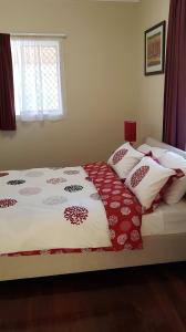 a bed with red and white blankets and pillows on it at Tillbrook Cottage in Perth