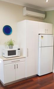 a white kitchen with a microwave and a refrigerator at Tillbrook Cottage in Perth