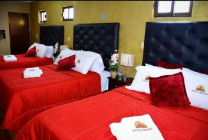 a hotel room with two beds with red sheets at Hotel Milenio Nanacamilpa Tlaxcala in Nanacamilpa