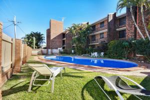 a yard with chairs and a swimming pool at Shandelle Apartments in Alexandra Headland