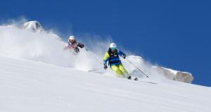 zwei Leute fahren eine schneebedeckte Piste hinunter in der Unterkunft Feichtlehnerhof in Ramsau am Dachstein