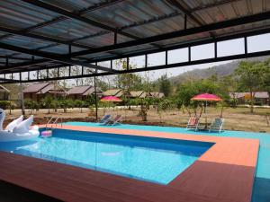 a large swimming pool with two chairs and umbrellas at Taakradan Valley Resort ท่ากระดานวัลเล่ย์ รีสอร์ท in Ban Wang Khun Knachen