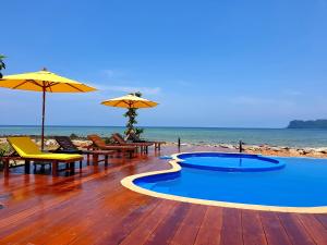 een terras met een zwembad en stoelen en parasols op het strand bij The Beach Resort & Residence - SHA Plus in Pathiu