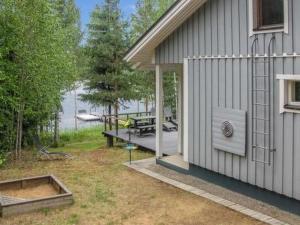 a house with a patio and a boat on the water at Holiday Home Lokki by Interhome in Vesijako