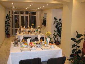 ブラショヴにあるPensiunea Wartheの白いテーブルクロスと食べ物を載せたテーブル