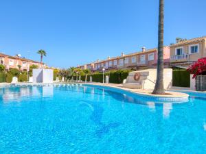 uma grande piscina com uma palmeira ao lado de um edifício em Holiday Home Campo Olivar by Interhome em Els Poblets