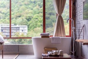 bagno con vasca di fronte a una finestra di Autumn Inn a Yangshuo