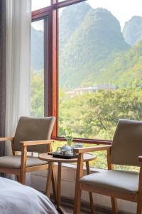um quarto com duas cadeiras e uma mesa em frente a uma janela em Autumn Inn em Yangshuo