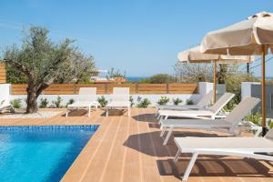 uma piscina com espreguiçadeiras brancas e um guarda-sol em Terpsis Pool Villa in Ilha de Rhodes