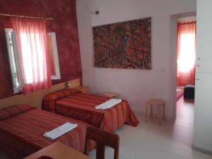 una camera d'albergo con due letti e un dipinto sul muro di Il Cortiletto a Trapani