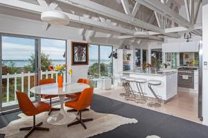 Christchurch - Art space, sea views, private في كرايستشيرش: مطبخ مع طاولة وكراسي برتقالية في الغرفة