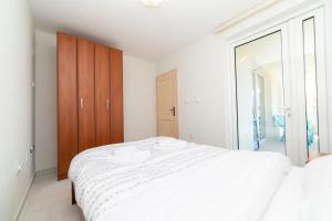 a bedroom with a white bed and a wooden cabinet at Apartmani Tripović in Tivat