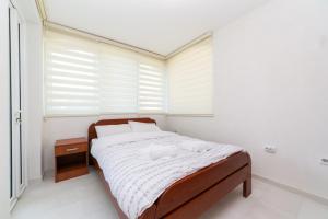 a bedroom with a bed and a window with blinds at Apartmani Tripović in Tivat