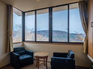 a room with two chairs and a table and large windows at HAKONE GORA ONSEN Hotel Kasansui in Hakone