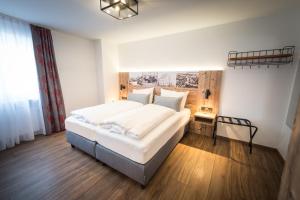 a bedroom with a large white bed and wooden floors at Hotel & Brauerei-Gasthof Neuwirt in Neuburg an der Donau