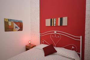 サン・ヴィート・ロ・カーポにあるCase vacanza Gioeleの赤い壁のベッドルーム(ベッド1台付)