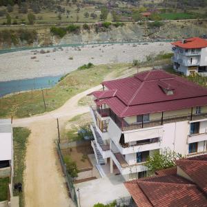 um edifício com um telhado vermelho ao lado de um rio em Hotel Villa Ago em Përmet