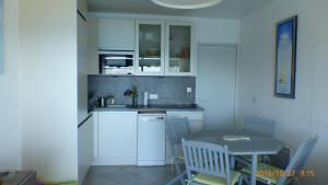 a kitchen with white cabinets and a table and a sink at Face à la mer Résidence Les Elmes in Banyuls-sur-Mer
