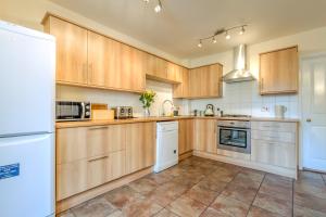 a kitchen with wooden cabinets and white appliances at The Headington Shark House - Oxford in Oxford