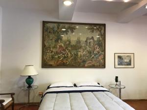 una pintura colgada en una pared sobre una cama en La Stalla, en Tuscania