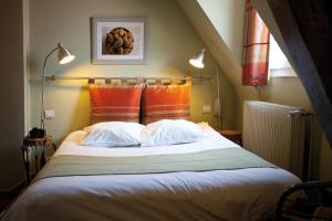 a bedroom with a large bed with orange and white pillows at Le Kléber Hôtel in Strasbourg