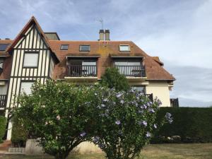 una casa con un árbol floreciente delante de ella en Picsine, Tennis résidence sévigné 300m mer, en Deauville