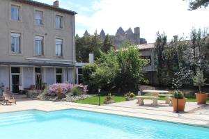 a swimming pool in a yard with a building at Carcas Hôtes Guest House in Carcassonne