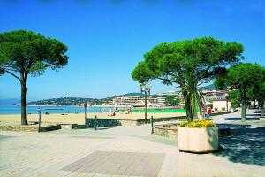 a park with a beach and trees and a bench at Hôtel Lou Paouvadou in Sainte-Maxime