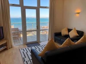 a living room with a couch and a view of the ocean at Seafront House, Westward Ho! in Westward Ho