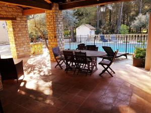 een patio met een tafel en stoelen en een zwembad bij Le Domaine d'Alèzen in Grans