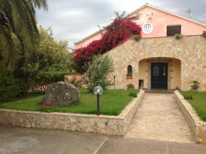 ein Steinhaus mit einem Garten und einer Auffahrt in der Unterkunft Hotel Fertilia in Fertilia