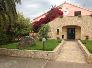 una casa in pietra con giardino e vialetto di Hotel Fertilia a Fertilia