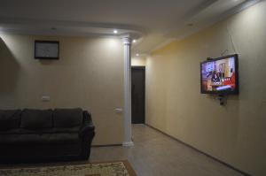 a living room with a couch and a television on a wall at Apartament 1 in Batumi