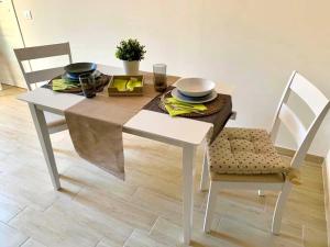 a white table with two chairs and a table with plates and bowls at Sweet Home in Francavilla di Sicilia