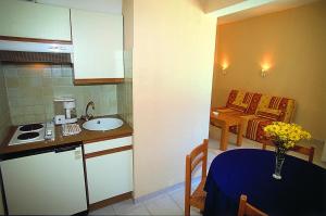 a small kitchen with a sink and a table in a room at Hôtel Lou Paouvadou in Sainte-Maxime