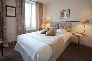 a bedroom with a large white bed and a window at Le Kléber Hôtel in Strasbourg