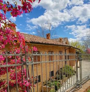 une clôture devant une maison ornée de fleurs roses dans l'établissement Luci sui Monti, à Sarnano
