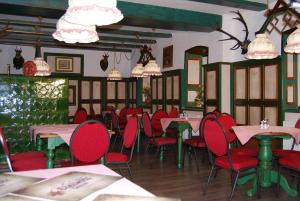 ein Esszimmer mit roten Stühlen und Tischen und Kronleuchtern in der Unterkunft Hotel 3 Gemsen in Mallnitz