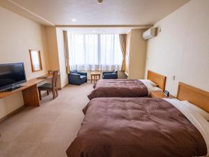 a hotel room with two beds and a television at HAKONE GORA ONSEN Hotel Kasansui in Hakone