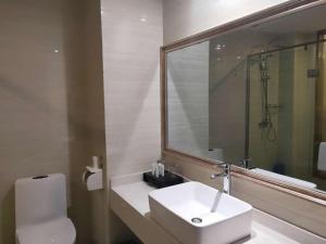 a bathroom with a sink and a toilet and a mirror at Dunhuang Dasheng Vacation Hotel in Dunhuang