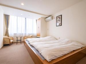 a bedroom with a large white bed and a table at HAKONE GORA ONSEN Hotel Kasansui in Hakone