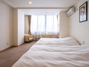 a bedroom with a white bed and a chair at HAKONE GORA ONSEN Hotel Kasansui in Hakone