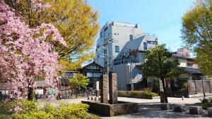 a park with flowering trees and a building at Midnight Rockers in Kanazawa