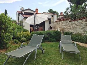 two lawn chairs and an umbrella in a yard at Villa Ana in Savudrija