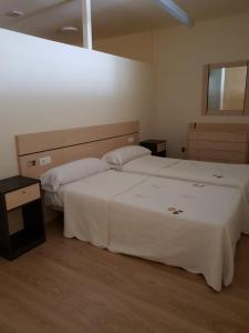 two beds in a hotel room with white sheets at Apartamentos Villava Pamplona in Villava